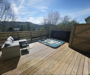 a deck with a hot tub and a couch on it at Waternish Apartment in Corpach