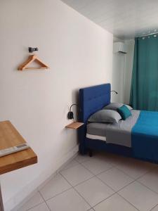 Schlafzimmer mit einem blauen Bett und einem Tisch in der Unterkunft Room A340 in Papeete