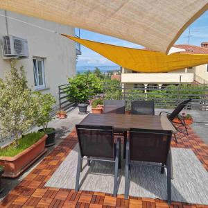 un patio con mesa, sillas y sombrilla amarilla en Rosemary apartment, en Izola
