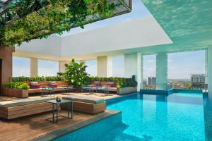 a pool with tables and chairs in a building at Aloft South Jakarta in Jakarta
