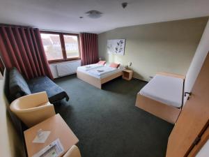 um quarto de hotel com uma cama e um sofá em Penzion Maděřič em Moravský Žižkov