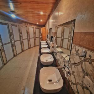 a bathroom with a row of sinks and toilets at EDM Hostel in Kangra