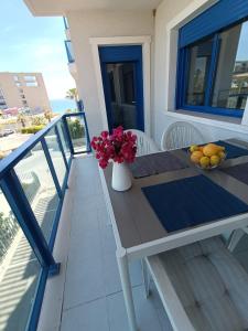 una mesa con un jarrón de flores y fruta en el balcón en Alicante Mar, en Alicante