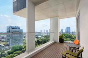 einen Balkon mit einem Tisch und Stühlen sowie großen Fenstern in der Unterkunft Aloft South Jakarta in Jakarta