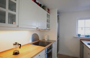 cocina con armarios blancos y encimera de madera en Modern Cottage Close To The Beach, en Vejby