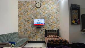 a living room with a couch and a tv on a wall at Red Rose Hotel in Bālākot