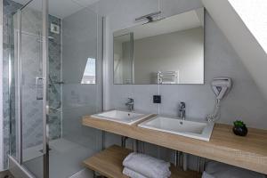 La salle de bains est pourvue d'un lavabo et d'une douche. dans l'établissement Appart Hôtel Le Liberté Vannes Centre-Ville, à Vannes