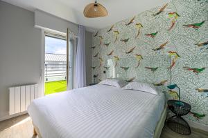 a bedroom with a bed with a bird wallpaper at Appart Hôtel Le Liberté Vannes Centre-Ville in Vannes