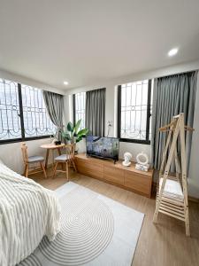 - une chambre avec un lit, une télévision et quelques fenêtres dans l'établissement Green Hotel & Apartment HN - by Bay Luxury, à Hanoï