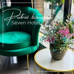 a green chair and a table with a potted plant at Seven Hotel Bytom - Katowice in Bytom
