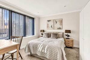 een witte slaapkamer met een bed, een bureau en ramen bij Modern Chic and Contemporary Retreat in Brentford in Brentford