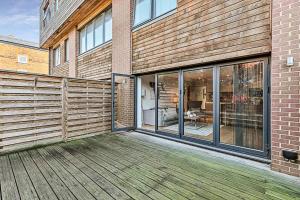 een houten terras met een gebouw met glazen ramen bij Modern Chic and Contemporary Retreat in Brentford in Brentford