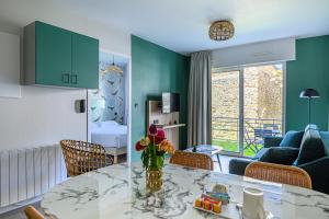 Una sala de estar con una mesa con un jarrón de flores. en Appart Hôtel Le Liberté Vannes Centre-Ville, en Vannes