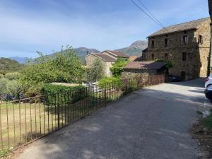 a fence in front of a house with mountains in the background at Maison de village in Valle-di-Rostino