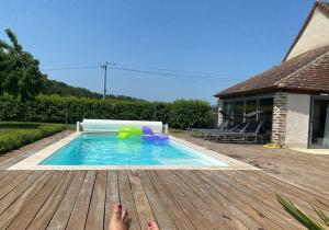 a person laying on a deck next to a swimming pool at Longère des 1001 étoiles in Renay