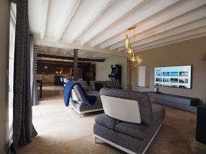 ein Wohnzimmer mit einem Sofa, Stühlen und einem TV in der Unterkunft Longère des 1001 étoiles in Renay
