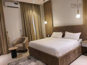 ein Hotelzimmer mit einem großen Bett und einem Stuhl in der Unterkunft Polo Grand Hotel in Maiduguri