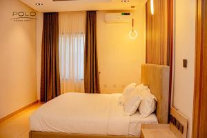 Schlafzimmer mit einem Bett mit weißer Bettwäsche und einem Fenster in der Unterkunft Polo Grand Hotel in Maiduguri