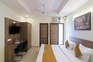 a bedroom with a bed and a desk and a television at Hotel Mint Residency - Dwarka Sector 9 in New Delhi
