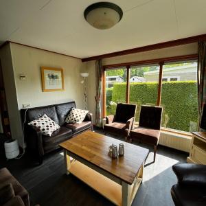 a living room with a couch and a coffee table at Camping Boslust, Bungalow de Koekoek in Putten