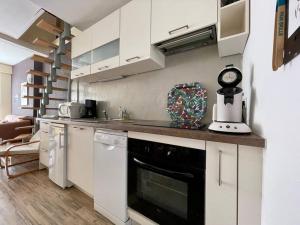a kitchen with white cabinets and a black oven at Maison des 4 Saisons by Melrose in Bayeux
