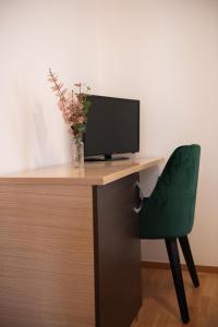 Elle comprend un bureau avec une télévision et une chaise verte. dans l'établissement Hotel Marina, à Fažana