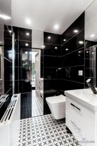 un bagno bianco e nero con servizi igienici e lavandino di Trzy Domki w Mielnie a Mielno