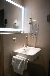 ein Badezimmer mit einem Waschbecken, einem Spiegel und Handtüchern in der Unterkunft Hotel Bleske im Spreewald in Burg