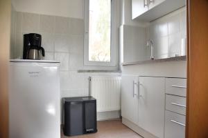 a white kitchen with a refrigerator and a window at Haus JuliaN Wohnung 2 in Ueckermünde