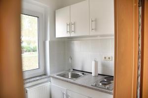 a white kitchen with a sink and a window at Haus JuliaN Wohnung 2 in Ueckermünde