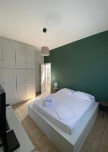 a bedroom with a large white bed with a green wall at Okio - Μονοκατοικία δίπλα στη θάλασσα in Elafonisos