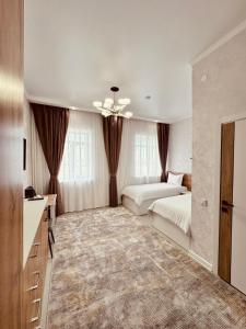 a large bedroom with two beds and a chandelier at Hotel Bereket Karaganda in Karagandy