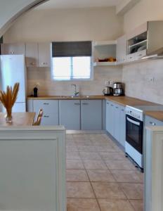 eine Küche mit weißen Geräten und einem Tisch darin in der Unterkunft Okio - Μονοκατοικία δίπλα στη θάλασσα in Elafonisos