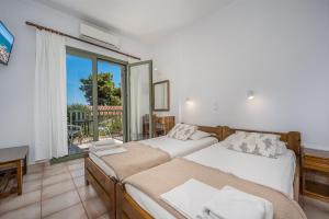 a bedroom with two beds and a large window at 123 Soleil Studios in Agia Marina Aegina