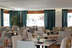 a dining room with tables and chairs and windows at Hotel MR Costa Blanca in Denia