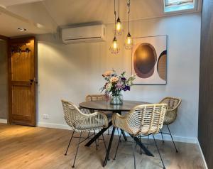 a dining room with a table with chairs and a vase of flowers at Bed and Breakfast Roodkapje in Kaatsheuvel