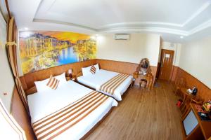 頭頓的住宿－Kieu Anh Hotel Vung Tau，墙上画画的房间里设有两张床