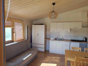 a kitchen with white cabinets and a couch in a room at Domki Zaczarowana Łąka w Borach Tucholskich in Wełpin