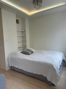 a white bedroom with a bed and a chandelier at Nyrenoverat i centrala Stockholm in Stockholm