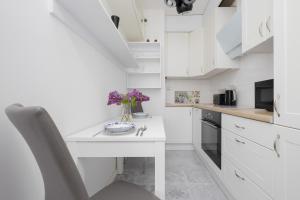 a kitchen with white cabinets and a table with flowers on it at Bright Studio Głowackiego for 2 People in Warsaw by Renters in Warsaw
