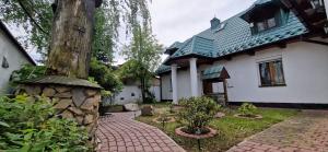 a house with a tree and a brick walkway at Dworek Wołyński - Winnica Zegartowice 