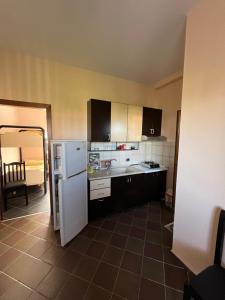 a kitchen with a white refrigerator and a tile floor at Hotel Elsaidi in Velipojë