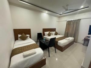 Habitación de hotel con 2 camas y mesa en Hotel Airport City en Bangalore