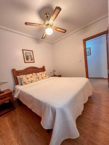 Un dormitorio con una cama con ventilador de techo. en Costa Oasis Residencia La Mirada, en Orihuela Costa