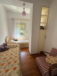 a bedroom with two beds and a chair and a window at Apartament Gjiri i Lalëzit in Durrës