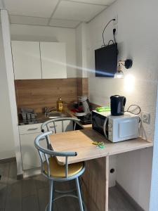 eine kleine Küche mit einem Tisch und einer Mikrowelle in der Unterkunft Résidence Sainte Thérèse - la villa Selva in Lourdes