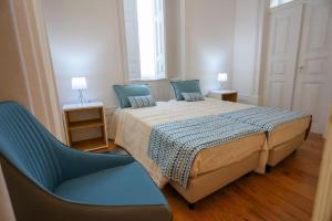 1 dormitorio con 1 cama y 1 silla azul en Casa Matriarca, en Santa Comba
