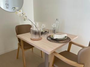 a wooden table with glasses and a vase on it at Cosy Diem Cap d'Agde in Cap d'Agde
