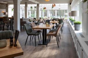 un restaurante con mesas y sillas de madera y ventanas en Boslodges Veluwe en Nunspeet