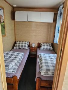 dwa łóżka w środku małego pokoju w obiekcie Domek letniskowy - niebieski całoroczny w mieście Stegers